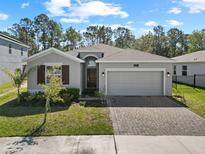 Charming single-story home featuring a two-car garage, brick-paved driveway, and manicured landscaping at 3002 Camden Way, Davenport, FL 33837