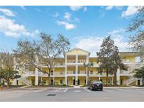 Bright yellow condo building with white balconies and well-maintained landscaping creating a welcoming curb appeal at 313 Lucaya Loop # 313, Davenport, FL 33897