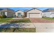 Charming single-story home features a brick driveway, blue shutters, and a well-maintained front yard at 485 Disa Dr, Davenport, FL 33837