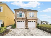 Charming two-story home featuring a stone facade and two-car garage and well manicured yard at 7623 Excitement Dr, Reunion, FL 34747