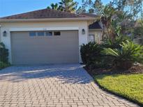 Charming single-story home featuring a paver driveway, tropical landscaping, and a neutral-tone garage door at 133 Indian Wells Ave, Kissimmee, FL 34759