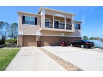 Three-story townhome exterior, showcasing garages, driveways, and a charming second-story balcony at 2120 Betsy Ross Ln, St Cloud, FL 34769