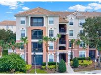 Stunning condo building with balconies and beautiful landscaping including green bushes and palm trees at 8300 Portofino Dr # 403, Davenport, FL 33896