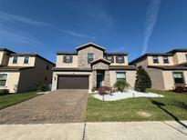 Beautiful two-story home with stone accents, a well-manicured lawn, and a brick paver driveway at 199 Macaulays Cv, Haines City, FL 33844