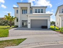 Striking two-story modern home featuring a gray garage, brick driveway, and manicured lawn at 2117 Pine Oak Loop, Davenport, FL 33837