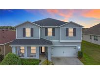Charming two-story home featuring gray siding, a welcoming front porch, and a well-manicured lawn at 2473 Biscotto Cir, Davenport, FL 33897