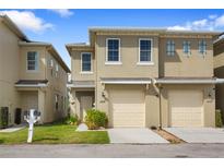 Charming townhome featuring a two-car garage, manicured lawn, and welcoming front entrance at 486 Lake Shore Pkwy, Davenport, FL 33896