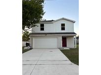 Two-story home with a two-car garage and a red front door, under a blue sky at 49 Inconnu Dr, Poinciana, FL 34759