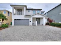 Stunning two-story home featuring a balcony and a two-car garage, complemented by a patterned brick driveway at 7649 Wilmington Loop, Kissimmee, FL 34747