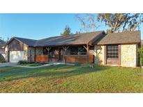 Charming single-story home featuring a stone facade, covered porch, and well-manicured lawn at 8568 Park Highland Dr, Orlando, FL 32818