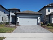 Charming single-Gathering home featuring a gray exterior, gray driveway, and a two-car garage at 1359 Greenfield Loop, Kissimmee, FL 34747