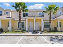 Inviting two-story townhome with a yellow exterior, well-kept landscaping, and prominent palm trees at 1645 Retreat Cir, Clermont, FL 34714
