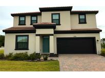 Charming two-story home featuring a brick driveway, neutral stucco, dark trim, and a teal front door at 220 Brookes Pl, Haines City, FL 33844