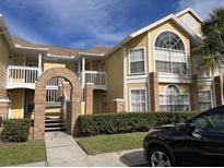Inviting yellow condo building with brick archway, well-maintained landscaping, and multiple levels of living at 2494 Sweetwater Club Cir # 55, Kissimmee, FL 34746