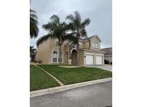 Stucco two-story home featuring a two-car garage, well-kept lawn, and tropical landscaping at 2663 Sand Hill Point Cir, Davenport, FL 33837
