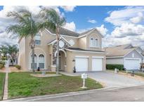 Charming two-story home featuring a 2-car garage, manicured lawn, and mature palm trees at 2663 Sand Hill Point Cir, Davenport, FL 33837