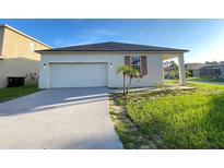 Charming single-story home with a well-maintained lawn, attached garage, and freshly painted driveway at 296 Sand Ridge Dr, Davenport, FL 33896