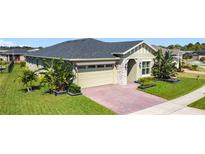 Beautiful single-story home showcasing manicured landscaping and a brick driveway leading to a two-car garage at 3240 Songbird Cir, Harmony, FL 34773
