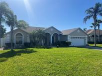 Inviting single-story home boasts lush lawn, arched entry, and well-manicured landscaping at 3303 Ann Arbor Ct, St Cloud, FL 34772