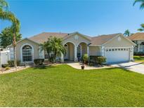 Beautiful single-story home with a well-manicured lawn, palm trees and a two car garage at 3303 Ann Arbor Ct, St Cloud, FL 34772