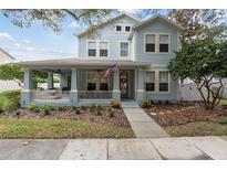Charming two-story home boasts a welcoming front porch, American flag, and beautiful landscaping at 3308 Cat Brier Trl, Harmony, FL 34773