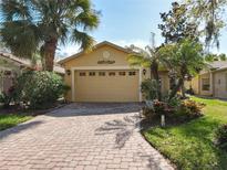 Charming home featuring a two-car garage, brick driveway, and lush tropical landscaping at 412 Grand Canal Dr, Kissimmee, FL 34759