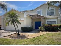 Charming two-story home featuring a stone-accented entrance, blue double doors, and lush landscaping at 4602 Cumbrian Lakes Dr, Kissimmee, FL 34746