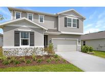 Beautiful two-story home featuring gray siding, dark shutters, and a two-car garage with manicured landscaping at 276 Hilltop Bloom Loop, Haines City, FL 33844