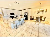 Bright kitchen featuring white cabinetry, stainless steel appliances, island with seating, and adjacent dining area at 3082 Royal Tern Dr, Winter Haven, FL 33881