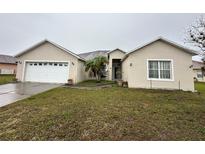 Inviting one-story home featuring an attached two-car garage and a well-maintained front yard with mature landscaping at 466 Peppermill Cir, Kissimmee, FL 34758