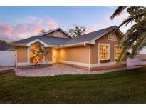 Charming single-story home featuring a landscaped front yard, brick-paved patio and inviting exterior lighting at 1049 Summer Lakes Dr, Orlando, FL 32835