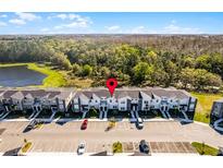 A beautiful aerial view of modern townhomes surrounded by lush greenery and a serene lake in the background at 2569 Reading Trl, Kissimmee, FL 34746