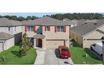 Two-story home with a two-car garage, red shutters, and a well-maintained lawn at 260 Willow Bend Dr, Davenport, FL 33897