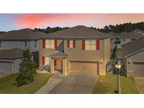 Two-story home showcasing red shutters and a well-manicured lawn at 260 Willow Bend Dr, Davenport, FL 33897