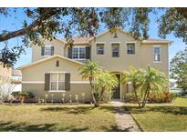 Inviting two-story home featuring a well-maintained lawn and decorative palm trees at 4061 Flowering Peach Ln, St Cloud, FL 34772