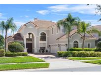 Stunning two-story home featuring a tile roof, arched windows, and meticulously landscaped front yard at 478 Chelsea Ave, Davenport, FL 33837