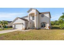 Two-story home with a stucco exterior, arched entryway, and an attached two-car garage at 5516 Willow Bend Trl, Kissimmee, FL 34758