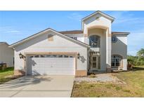 Front exterior showing a two-story home with attached two car garage and manicured landscaping at 5516 Willow Bend Trl, Kissimmee, FL 34758
