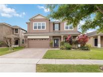 Charming two-story home boasts lush landscaping, a brick-paved driveway, and a welcoming front entrance at 654 Cortona Dr, Orlando, FL 32828
