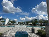 Resort-style pool area with cabanas, loungers and palm trees providing a relaxing oasis at 7740 Sandy Ridge Dr # 1, Kissimmee, FL 34744