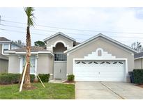 Charming single-story home featuring a well-manicured lawn and a two-car garage at 8204 Fan Palm Way, Kissimmee, FL 34747