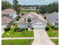 Charming single-story home with a well-manicured lawn, mature trees, and a two-car garage at 8204 Fan Palm Way, Kissimmee, FL 34747