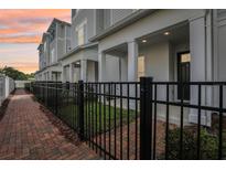 Charming townhomes featuring brick sidewalks, black metal fencing, and welcoming covered entrances at 117 E Concord St # 8, Orlando, FL 32801