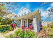 Inviting two-story home featuring a charming front porch with brick pillars and colorful landscaping at 13041 Gabor Ave, Orlando, FL 32827