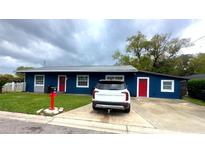 Charming home with blue exterior, red doors, well-maintained lawn, and ample driveway parking at 50 S Lavon Ave, Kissimmee, FL 34741