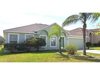 Charming single-story home with a well-maintained lawn, lush landscaping, and a two-car garage at 502 Woodland Creek Blvd, Kissimmee, FL 34744