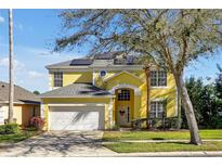 Two-story yellow home with a white garage door, arched entry, and solar panels at 8401 Secret Key Cv, Kissimmee, FL 34747