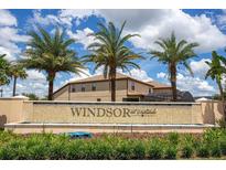 Windsor at Westside community entrance featuring a stone sign, palms, and lush landscaping under a bright, cloudy sky at 8936 Sydney Ave, Kissimmee, FL 34747