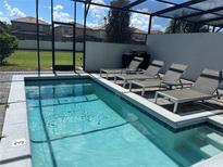 Sparkling screened-in pool with sun loungers, offering a private outdoor oasis at 8936 Sydney Ave, Kissimmee, FL 34747
