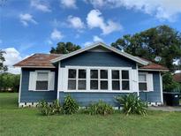 Charming blue home with white trim, surrounded by green grass and lush plants under a bright blue sky at 1011 26Th Street, Orlando, FL 32805